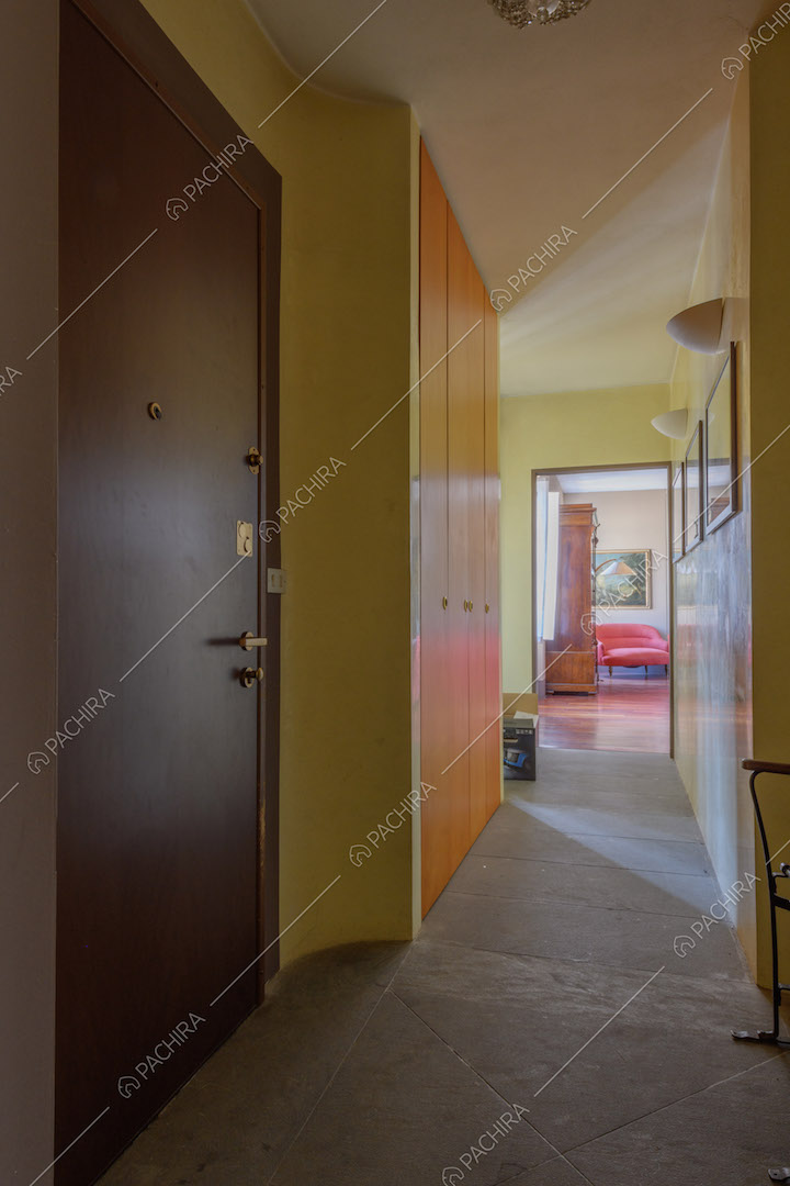 Ingresso con pavimento in pietra, pareti gialle e vista sulla zona living