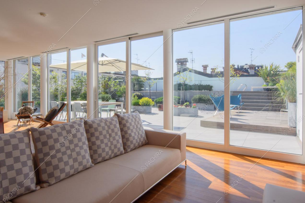 Luminosa zona living con pavimento in parquet, divano beige e vista sulla terrazza