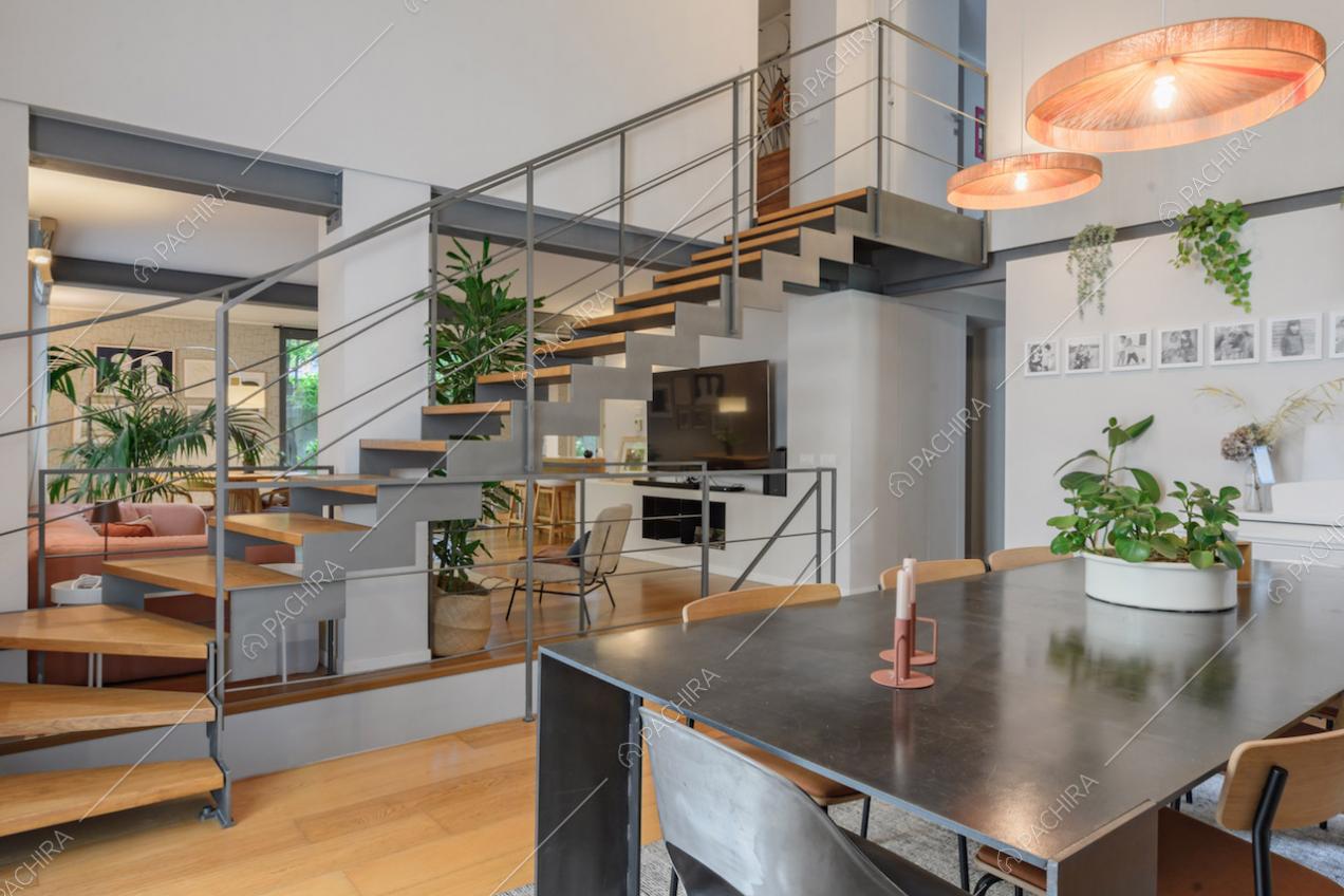Tavolo da pranzo in metallo nella sala con scale e alto soffitto