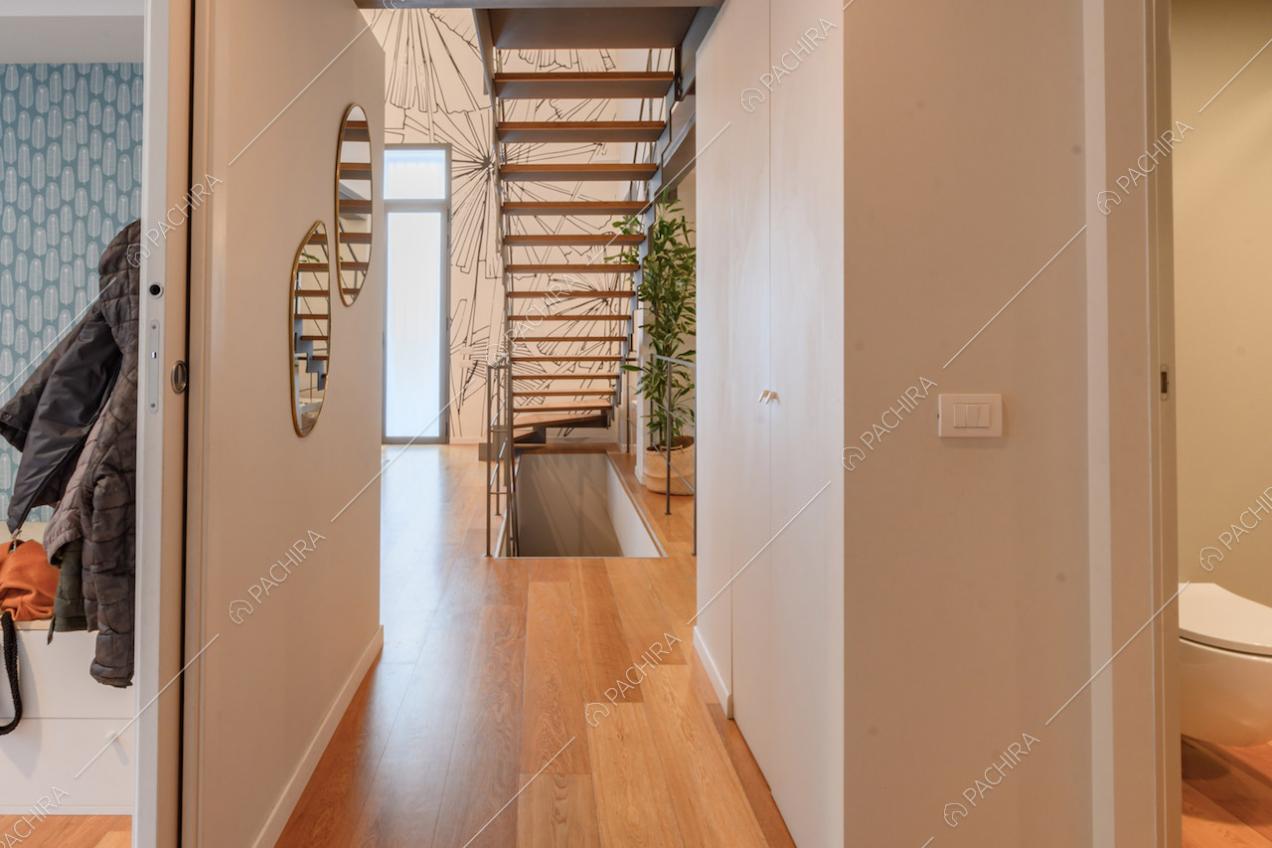 Corridoio con pavimento in parquet e vista sul vano scale e sulla carta da parati
