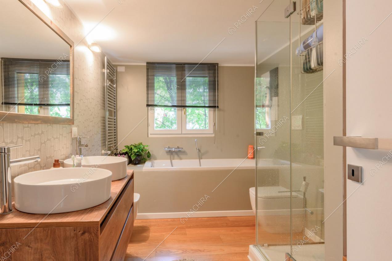 Pavimento in parquet nel bagno con vasca, box doccia e doppio lavandino