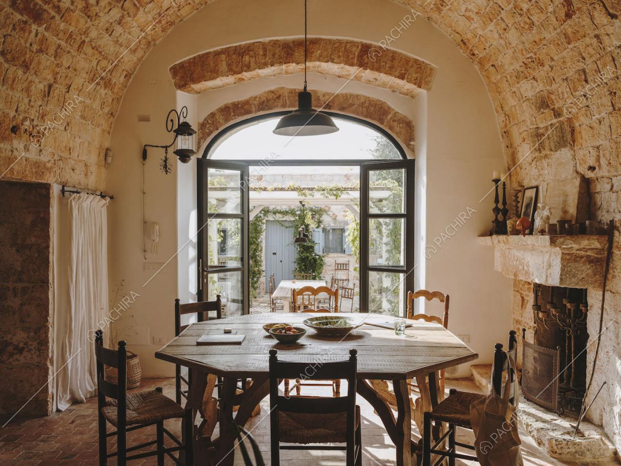 Tavolo da pranzo nella sala con camino illuminata dalla porta-finestra