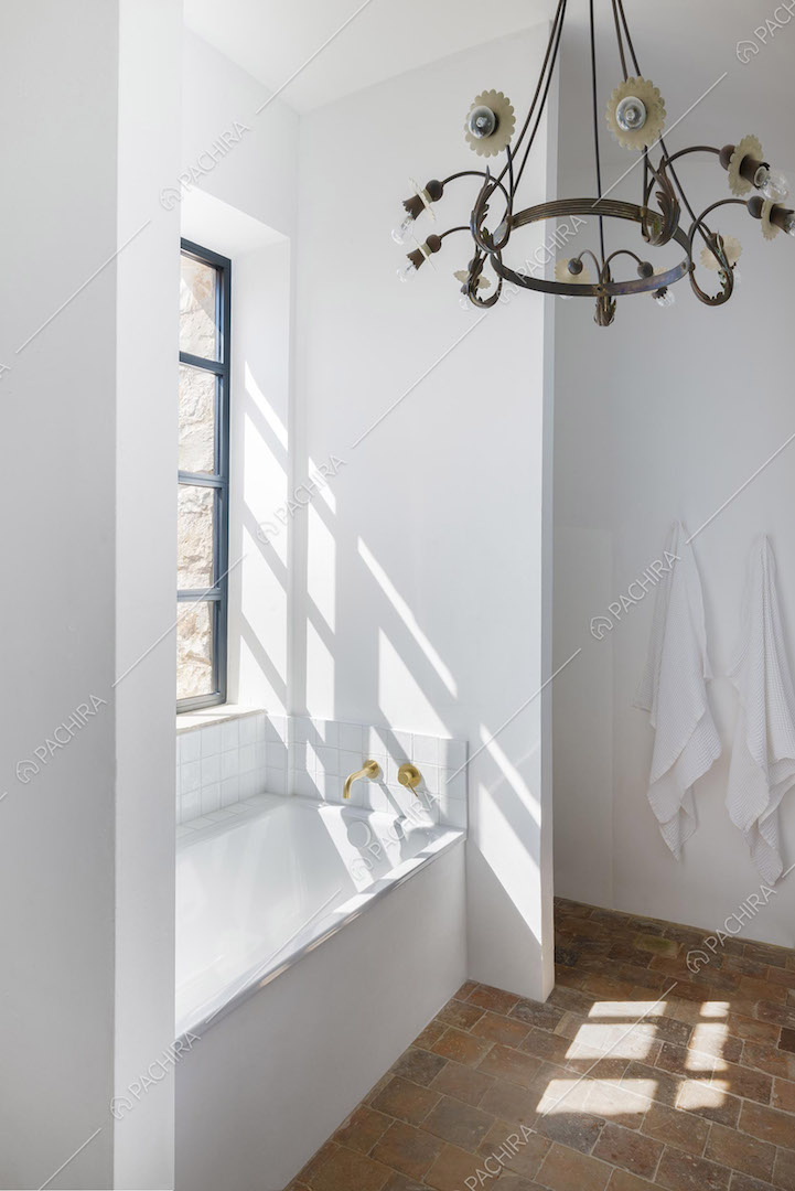 Luminoso bagno con pareti bianche, vasca e pavimento in cotto