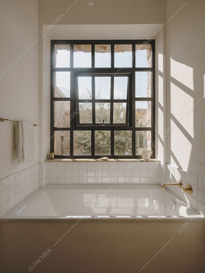 Ampia vasca nel luminoso bagno con pareti bianche e grande vetrata