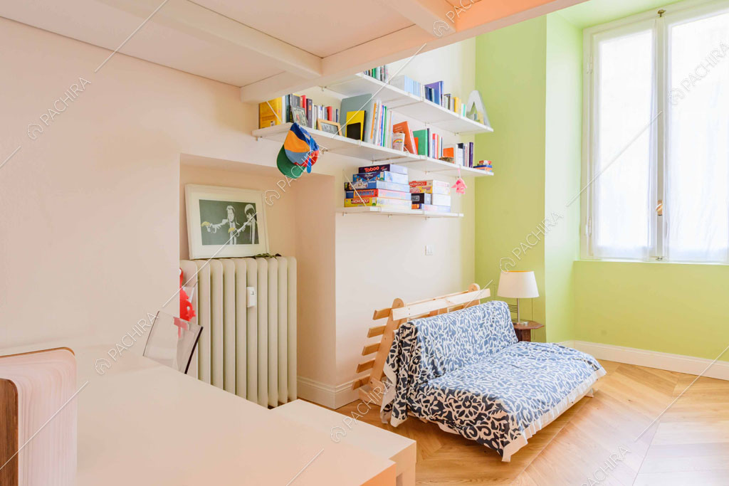 Scrivania e divano letto nella camera con parete verde e pavimento in parquet