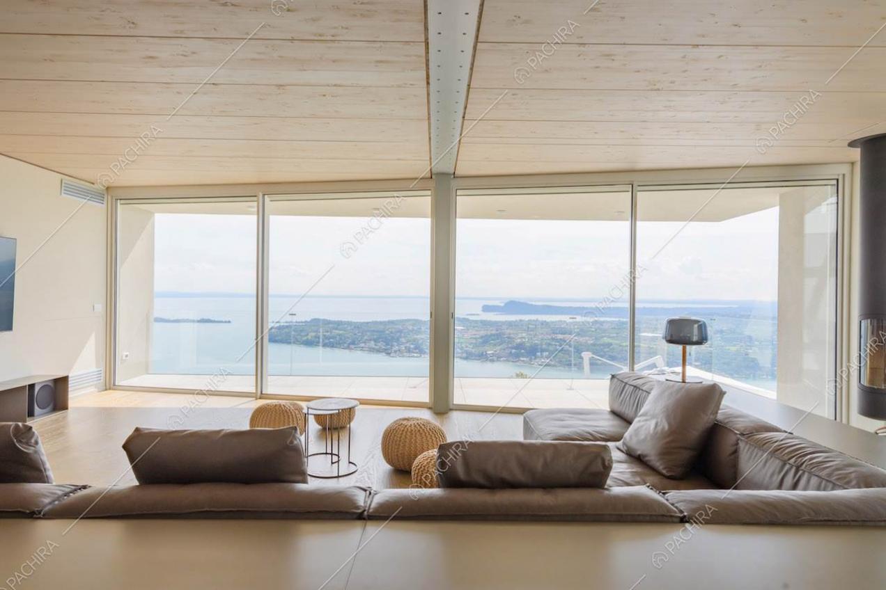 Divano marrone in pelle nel salotto con soffitto in legno e grandi vetrate