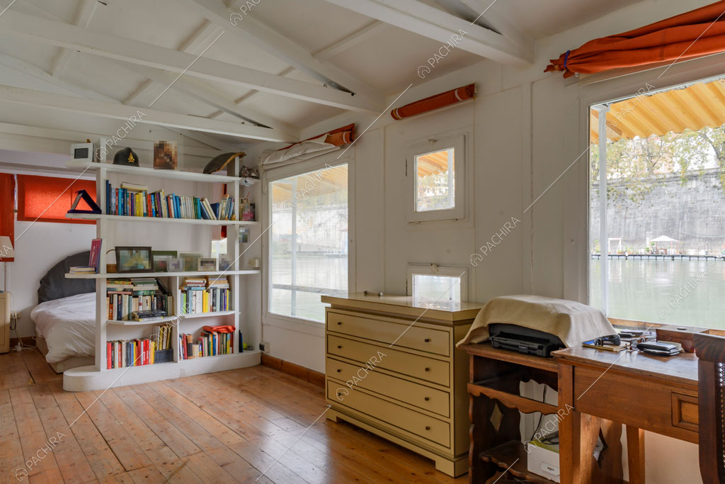 Travi a vista sul soffitto bianco, pavimento in parquet e letto matrimoniale