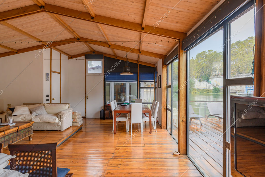 Grandi vetrate riempiono di luce naturale la sala con pavimento in parquet e soffitto in travi in legno