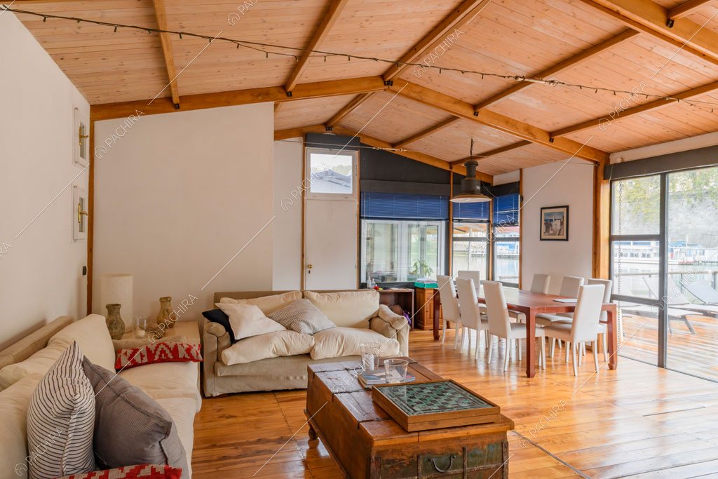 Travi in legno a vista sul soffitto, pavimento in parquet e grandi vetrate con vista sul Tevere