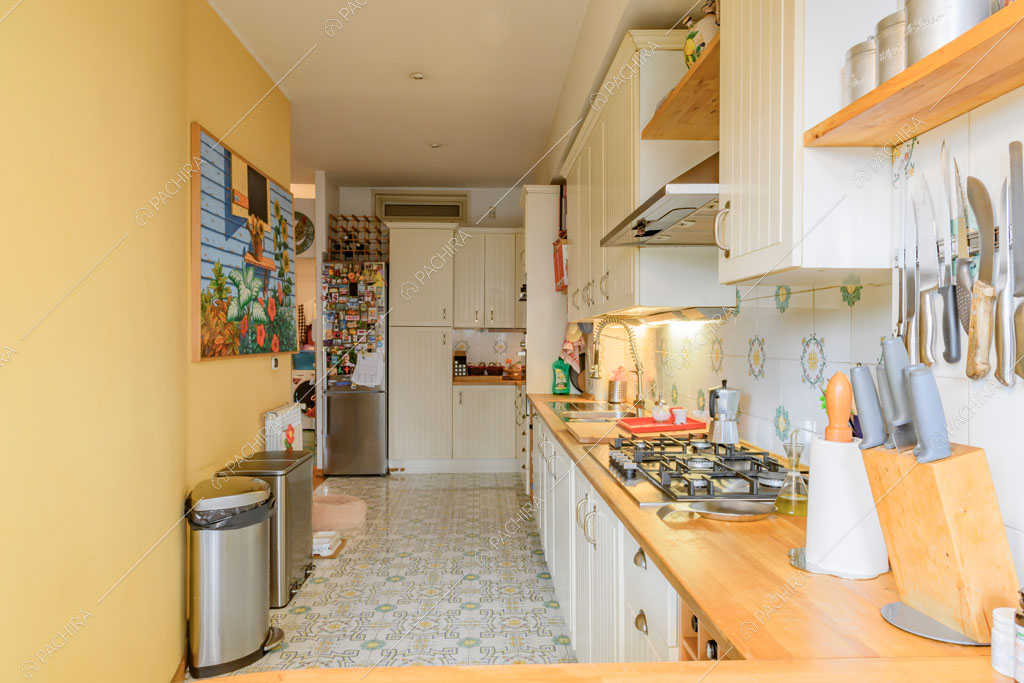 Cucina a parete bianca con fornelli a gas e pavimento in piastrelle