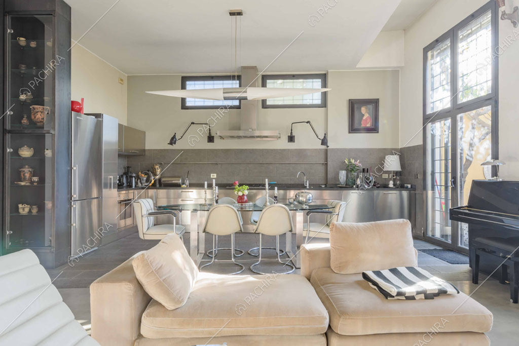 Pouf beige nella luminosa zona living con pavimento in cemento lisciato e cucina a parete