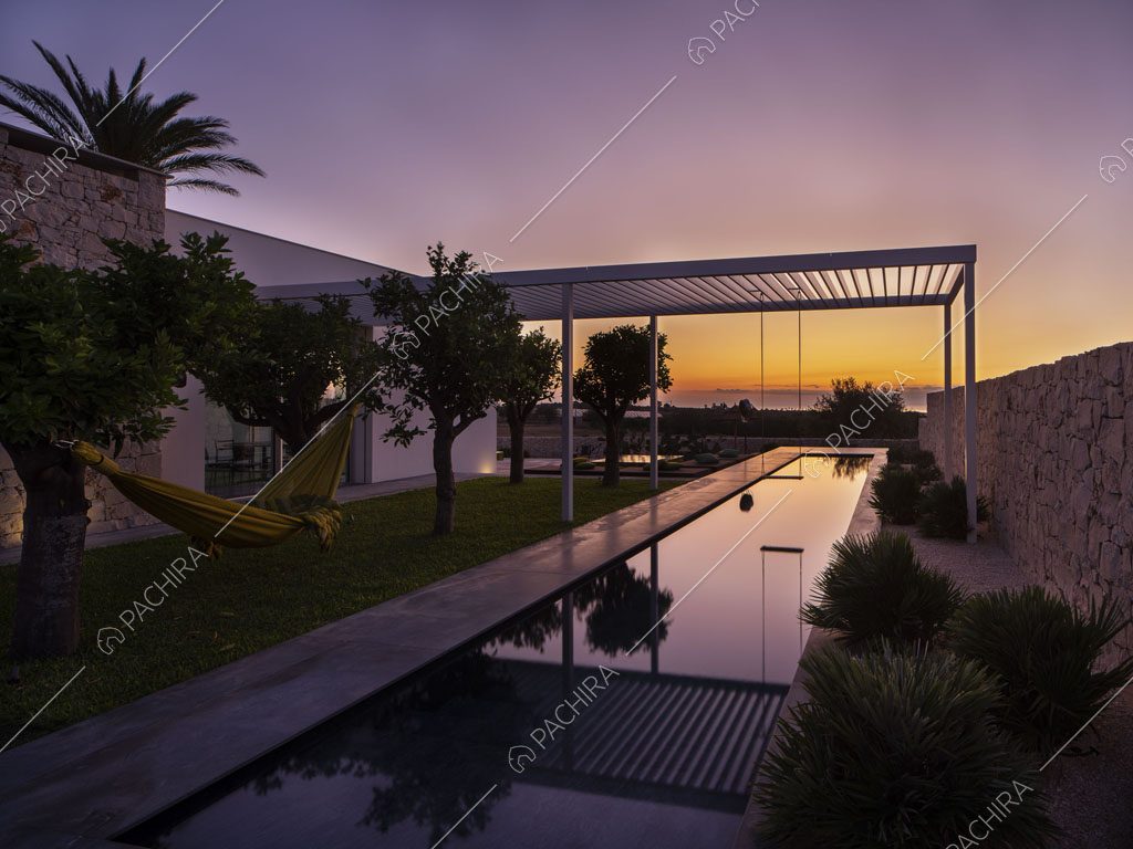 Vista sulla lunga piscina con patio bianco e esterni bianchi