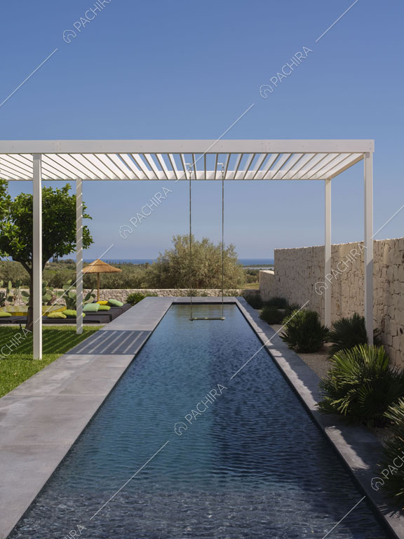Lunga piscina nel giardino circondato dalle mura di pietre bianche