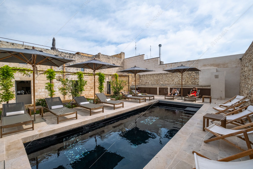 Piscina con numerose sdraio e lettini nel giardino della location