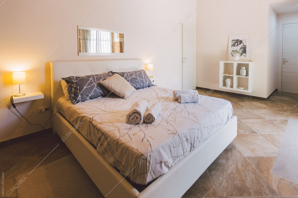 Camera da letto matrimoniale con pavimento in marmo della villa Hibiki, location in stile moderno a Siracusa