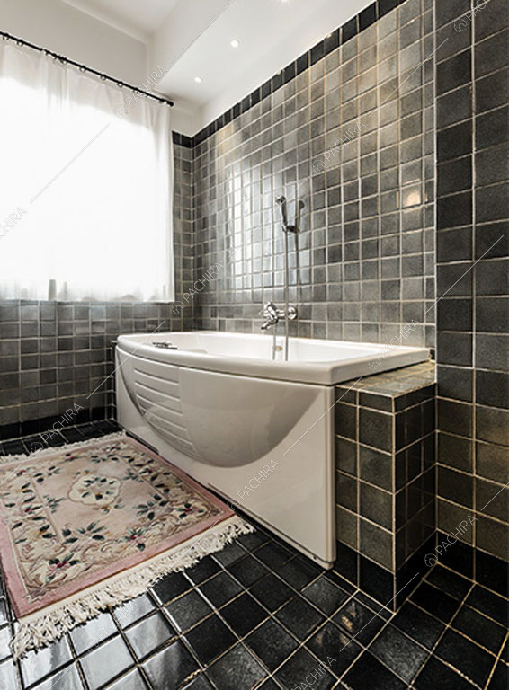 Bagno con piastrelle nere dello chalet Betel, location in stile rustico a Lecco