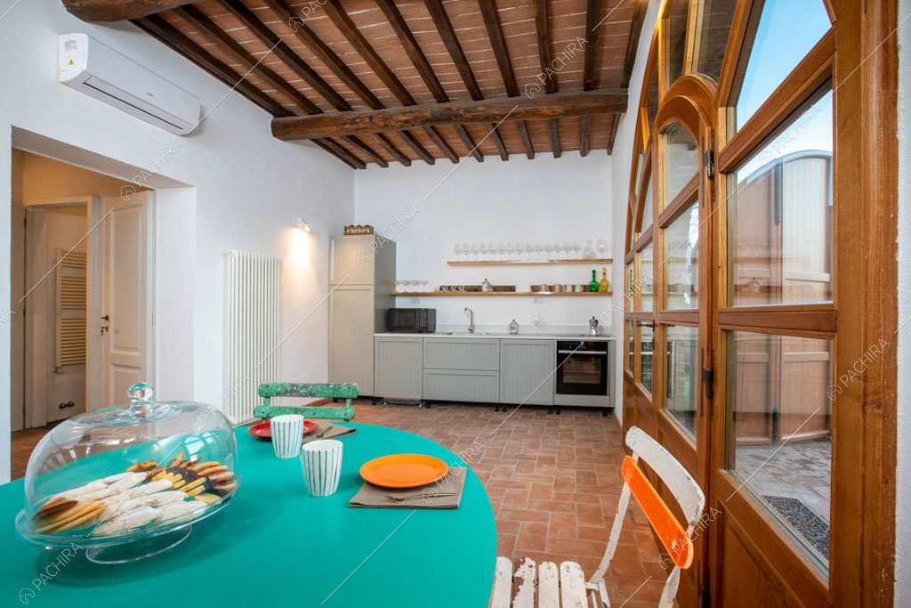 Cucina a parete con travi a vista sul soffitto nella villa Bardenas, location in stile rustico a Siena