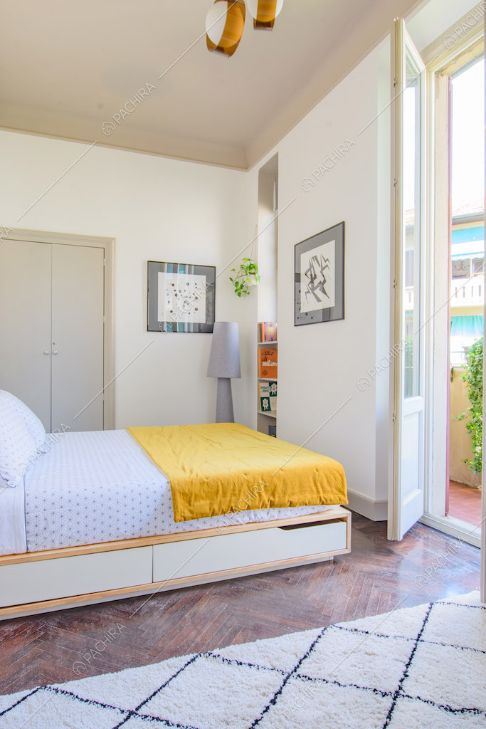 Luminosa camera da letto matrimoniale con pavimento in parquet a spina di pesce