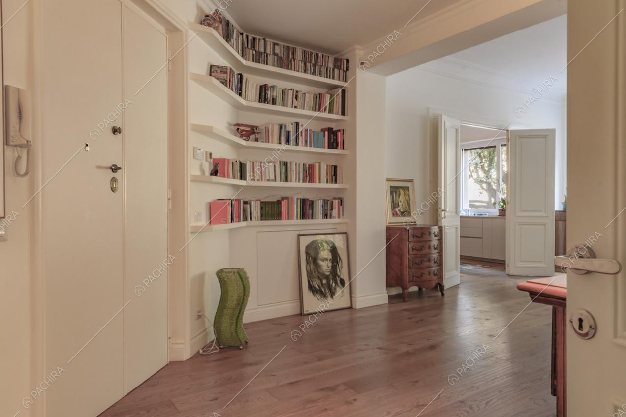 Atrio dalle pareti bianche con boiserie, con libreria e vista sulla cucina