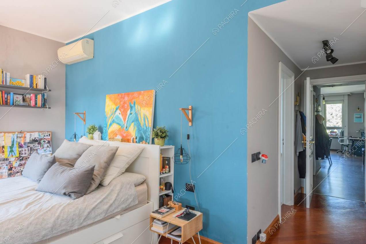 Camera da letto con parete azzurra e pavimento in parquet