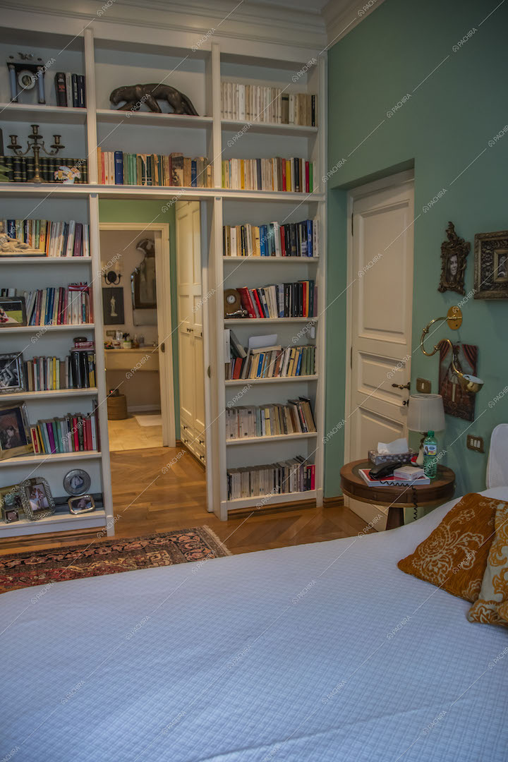 Letto matrimoniale nella camera con libreria a muro e vista sul bagno