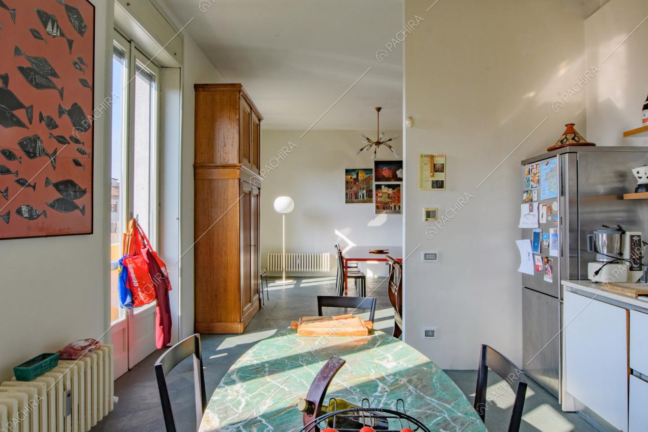 Piano in marmo verde ovale del tavolo da pranzo nella cucina a parete con porte-finestre