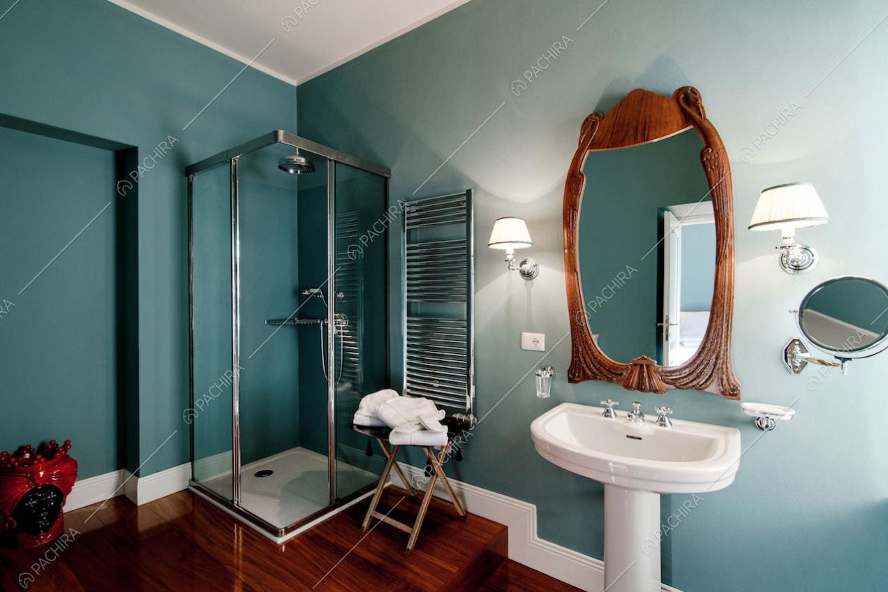 Bagno con pavimento in parquet e pareti verde salvia