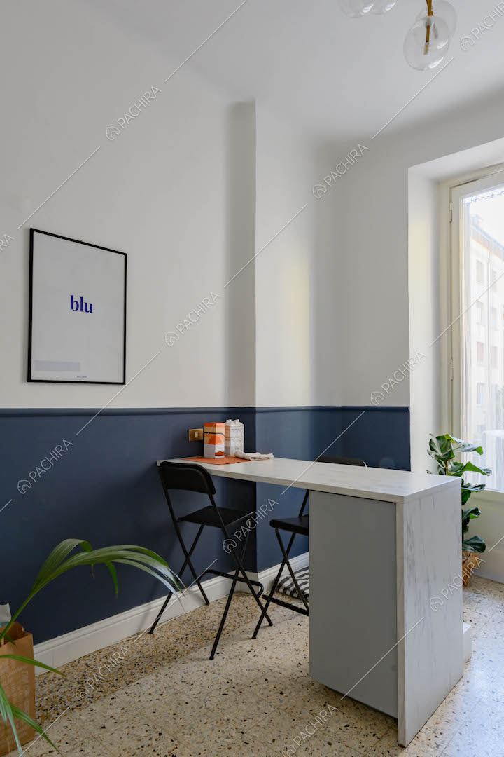 Tavolo da pranzo nella luminosa cucina con pavimento in graniglia e parete bianca e blu
