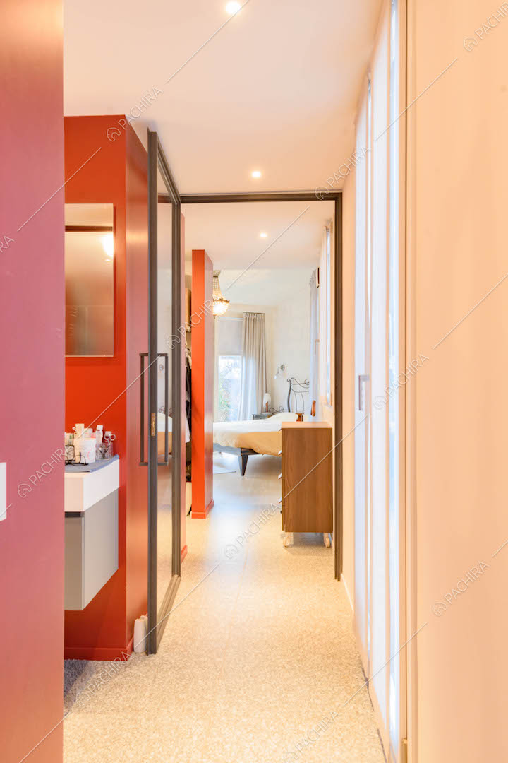 Dal bagno con pareti rosse vista sulla camera da letto e scorcio sulla cabina armadio