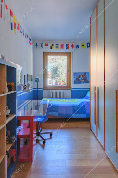 Camera da letto con scrivania, pavimento in parquet e armadio a tutta parete
