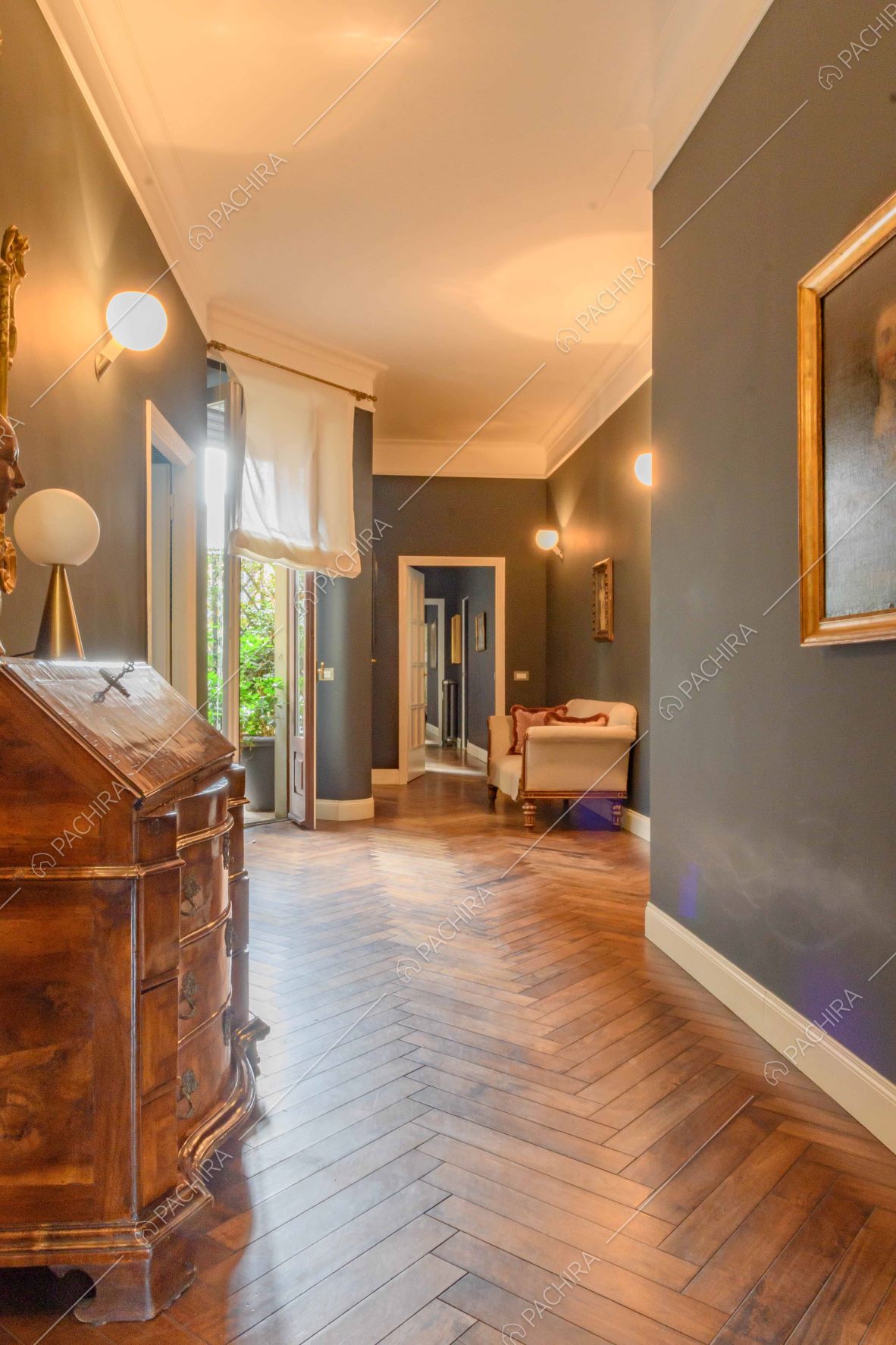 Lungo corridoio dalle pareti blu, con pavimento in parquet e porta-finestra per accedere alla terrazza