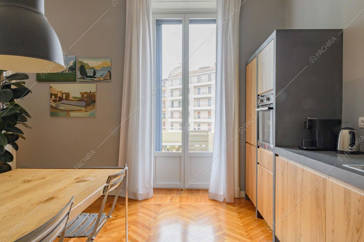 Nella cucina con pavimento in parquet a spina di pesce tavolo da pranzo in legno e lampadari di design