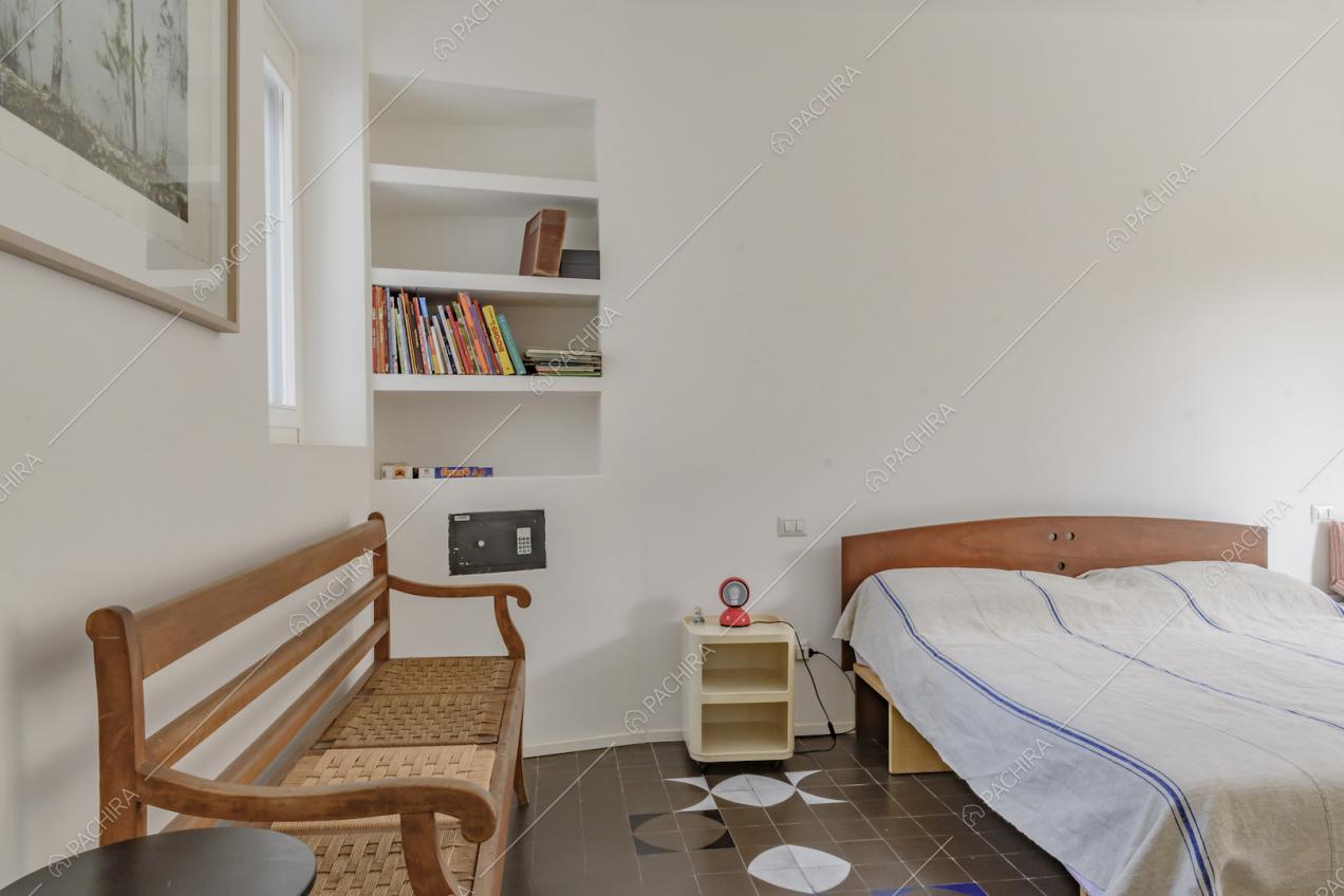Camera da letto matrimoniale con panca in legno e libreria a muro