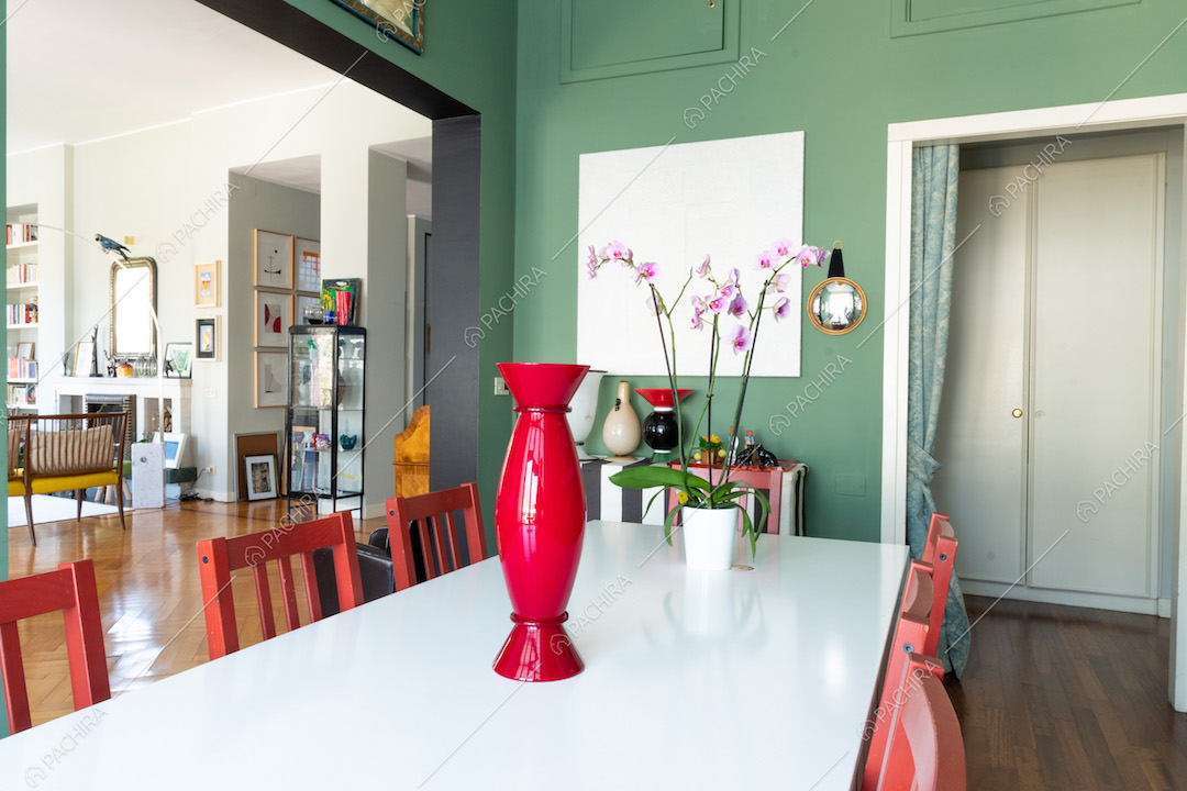 Dalla sala da pranzo vista sul salotto con pavimento in parquet a spina di pesce e camino