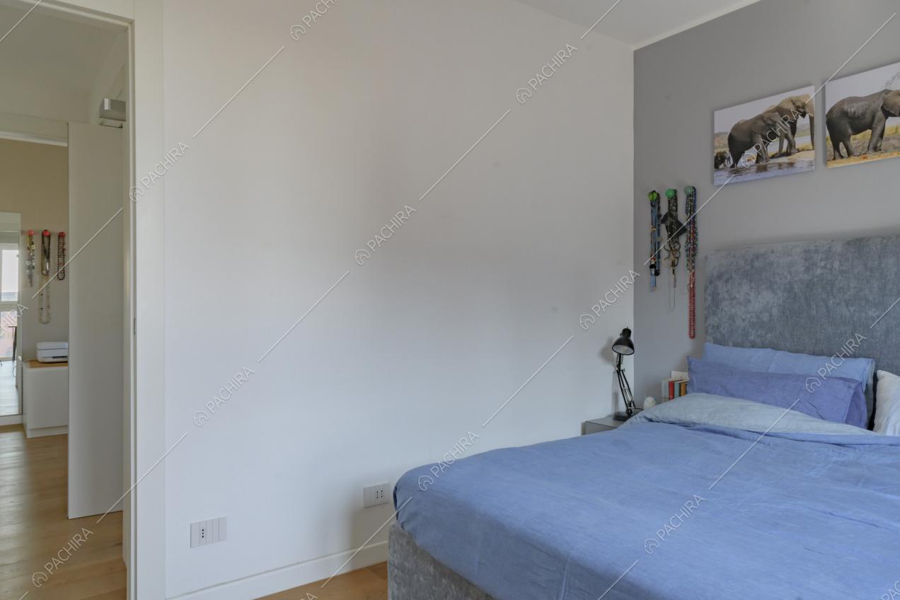 Camera da letto matrimoniale dalle pareti bianche e grigie e pavimento in parquet