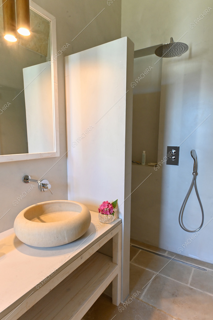 Bagno dai toni chiari, con pavimento in pietra e lampada di design