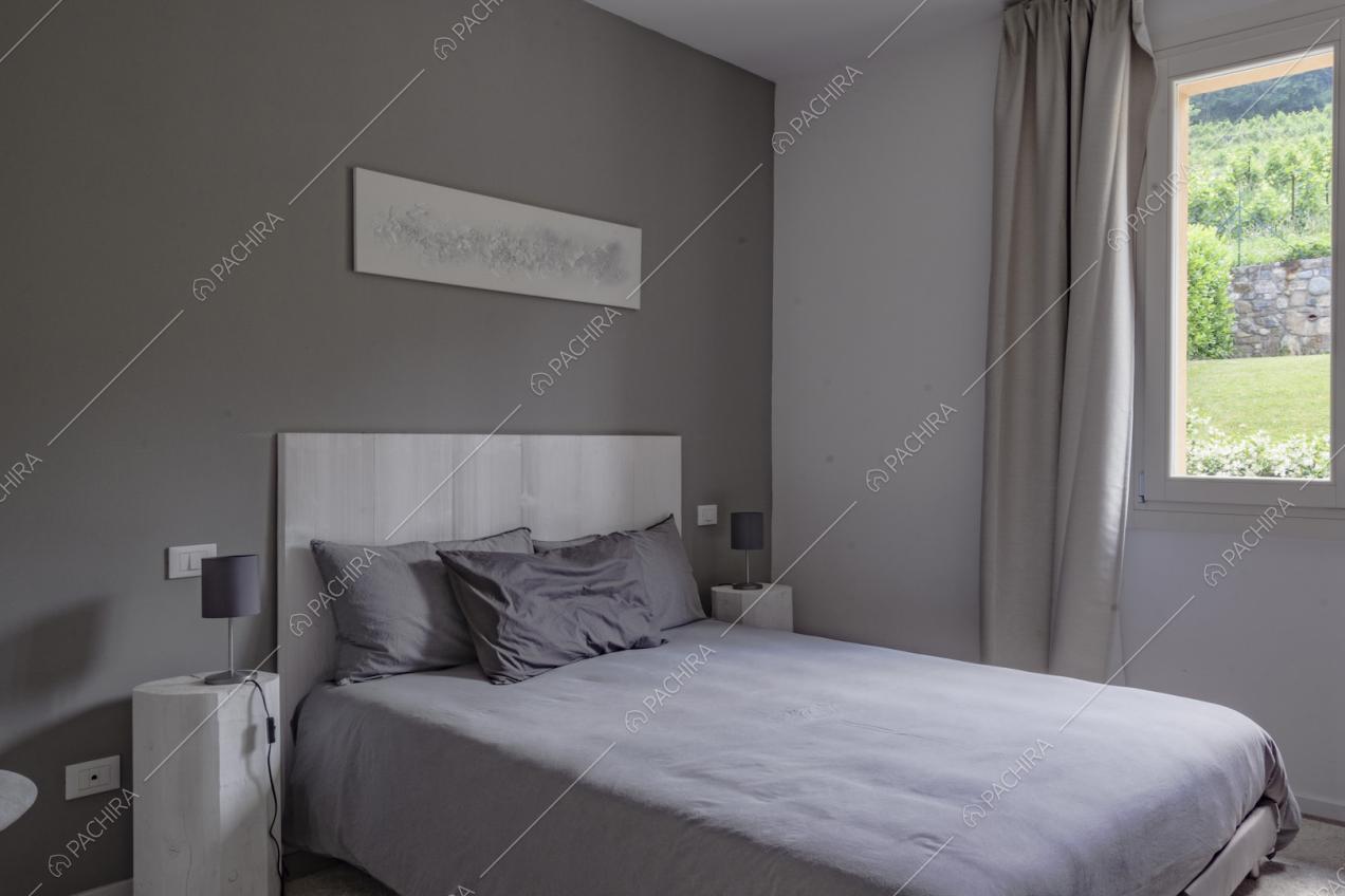 Parete color grigio e letto matrimoniale con cuscini