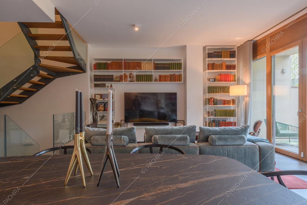 Dal tavolo da pranzo in marmo vista sul divano e sulla tv nella sala con pareti bianche