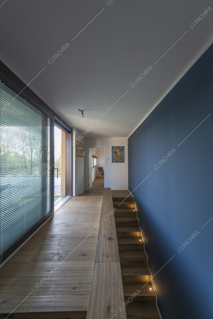 Corridoio con porte-finestre scorrevoli, parete blu e scale in legno