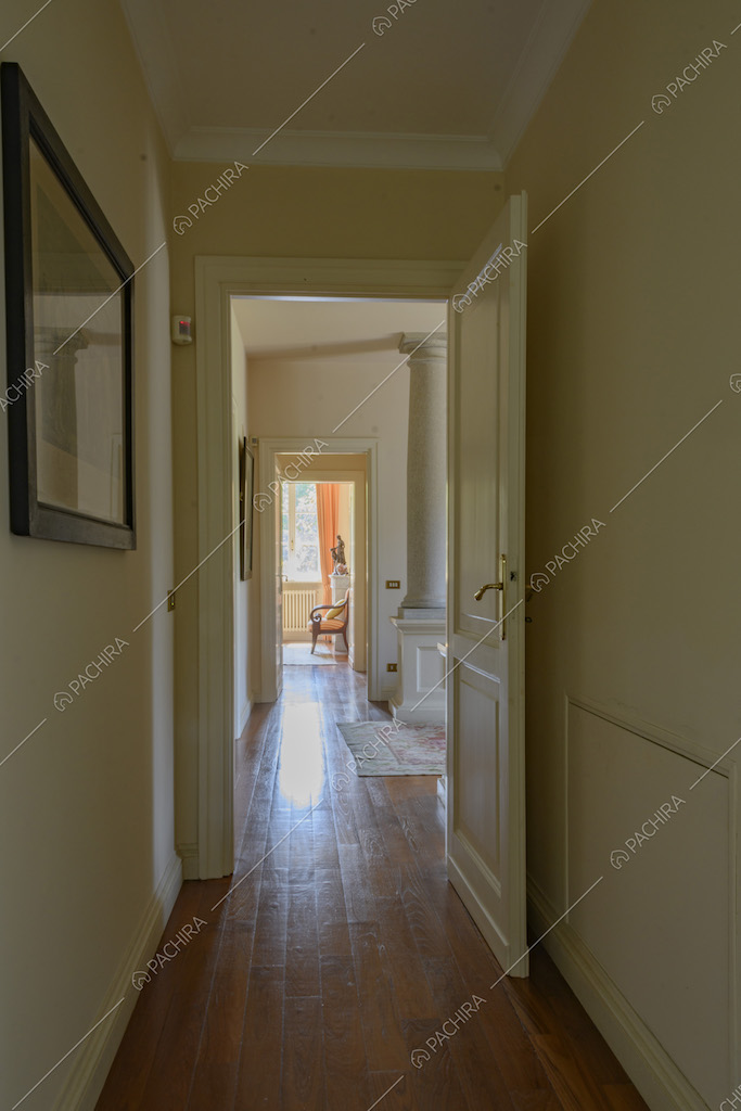 Lungo corridoio con porte e pareti bianche e parquet