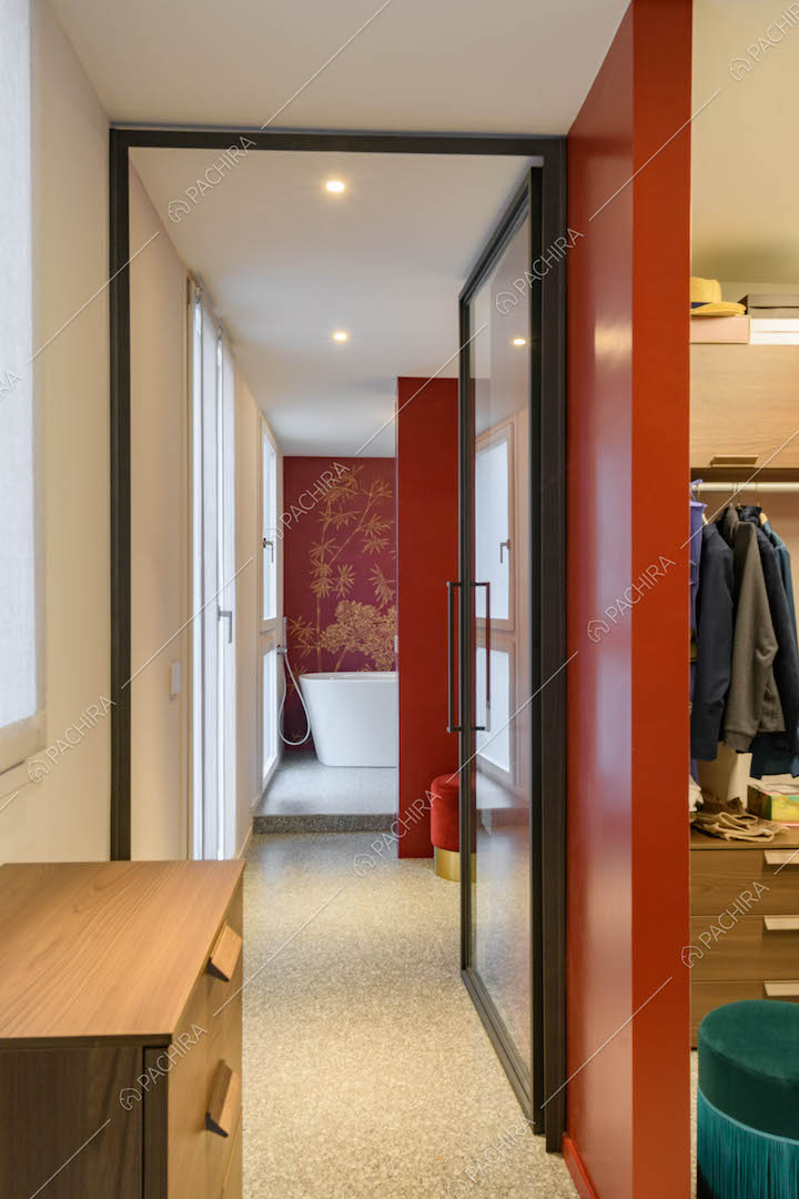 Scorcio sulla cabina armadio con parete rossa e sul bagno con vasca e carta da parati