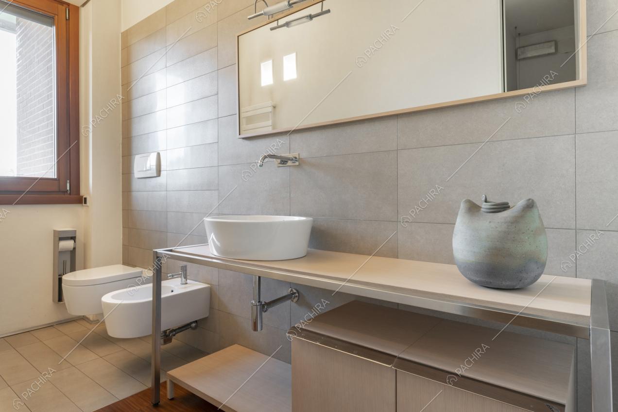 Bagno con pareti e pavimento rivestiti in piastrelle chiare