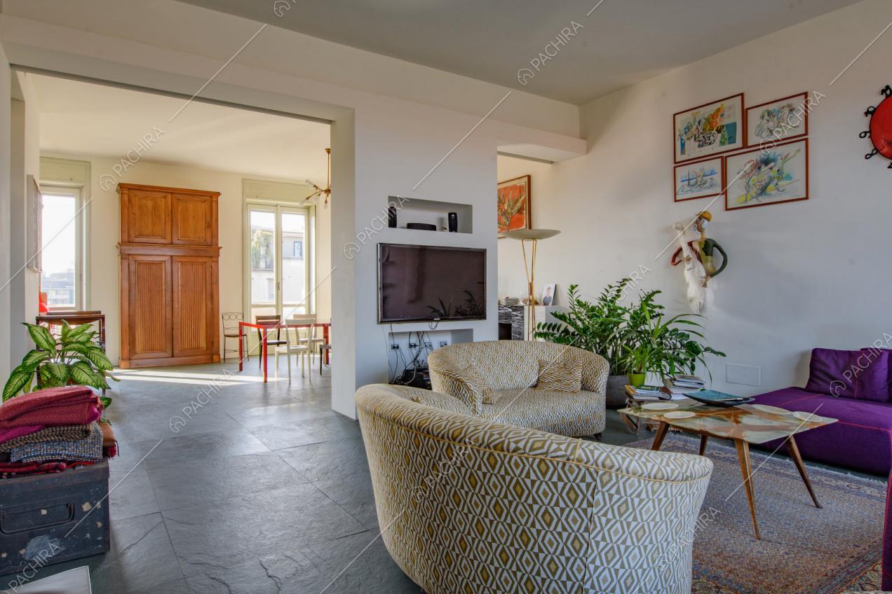 Divani nella luminosa zona living con tavolo da pranzo e pareti bianche