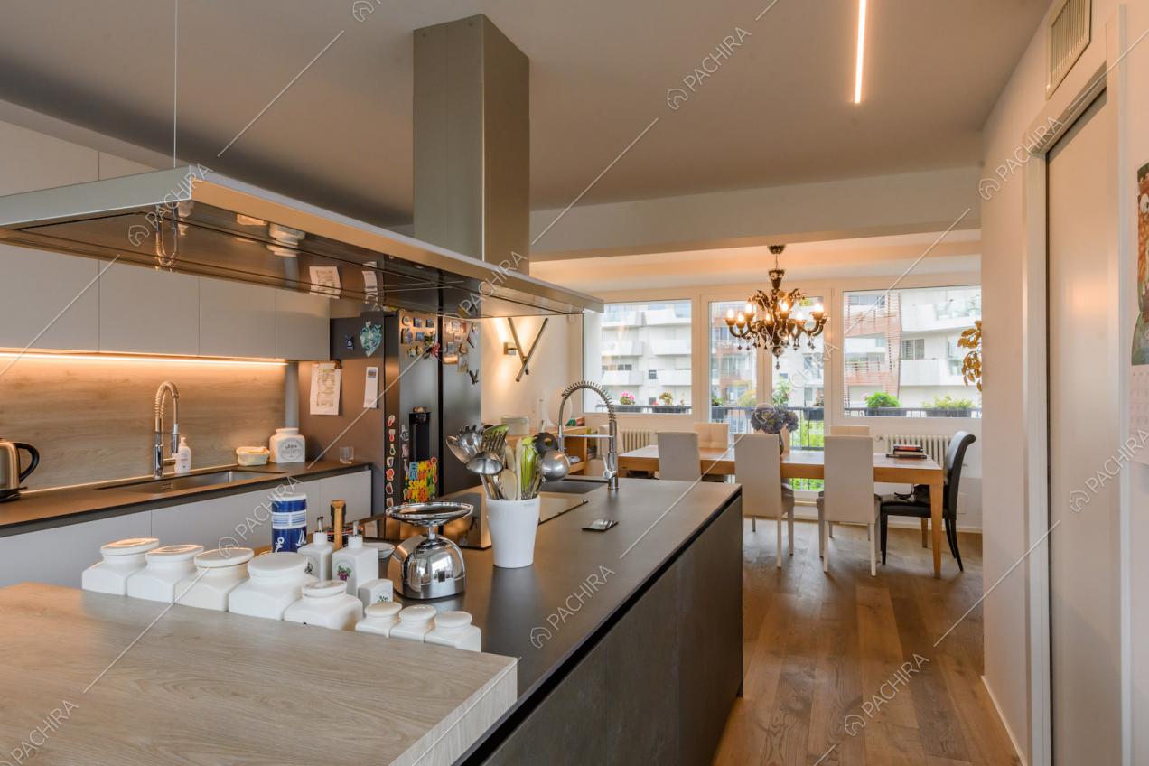 Isola nera della cucina con pavimento in parquet e vista sul tavolo da pranzo