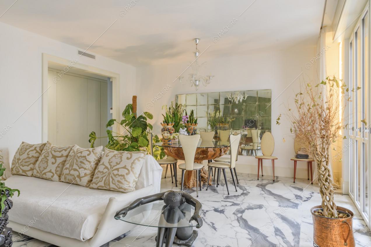 Sala dalle pareti bianche, con pavimento in marmo, divano bianco e tavolo da pranzo di design