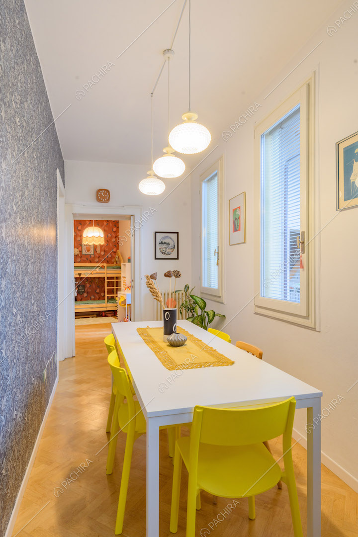 Tavolo da pranzo bianco, sedie gialle, carta da parati e pavimento in parquet
