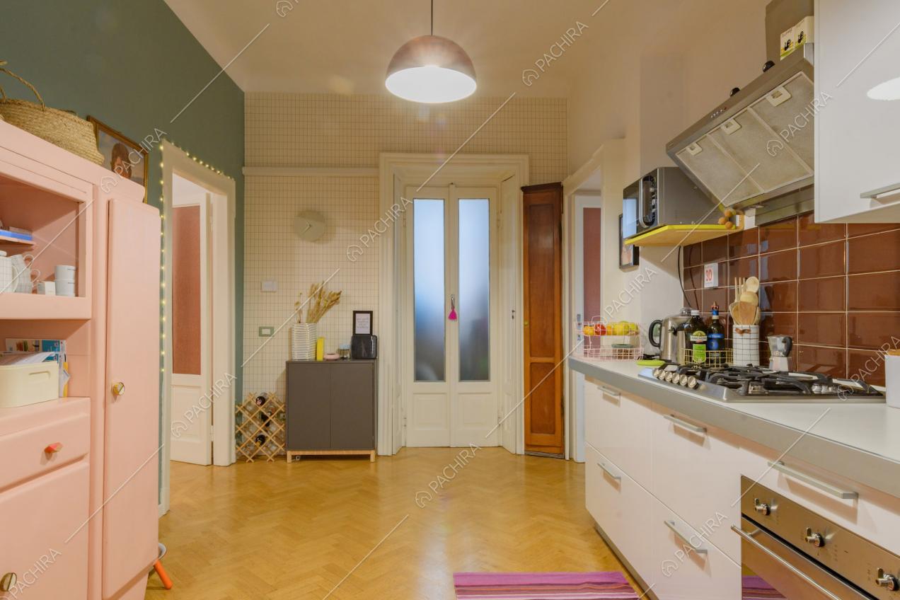 Paraschizzi in piastrelle marroni e fornelli a gas nella cucina con pavimento in parquet