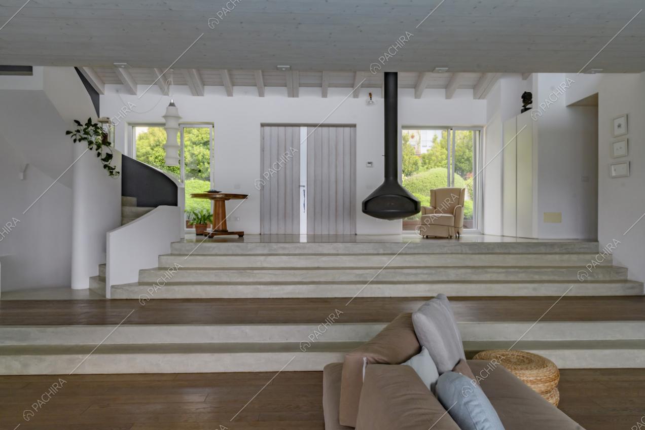 Dal divano marrone della sala con pavimento in parquet, vista sull'ingresso rialzato e sulle scale