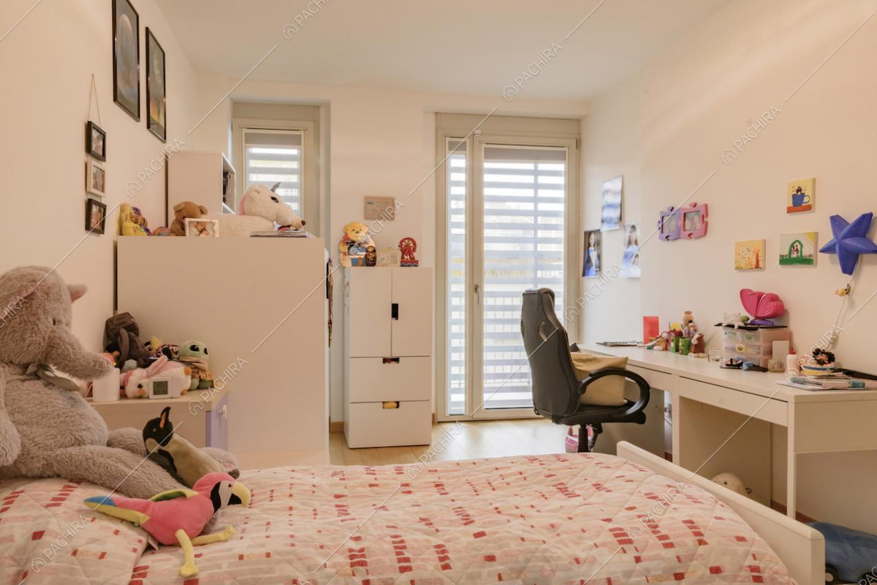 Camera da bambini con scrivania e porta-finestra per accedere al balcone