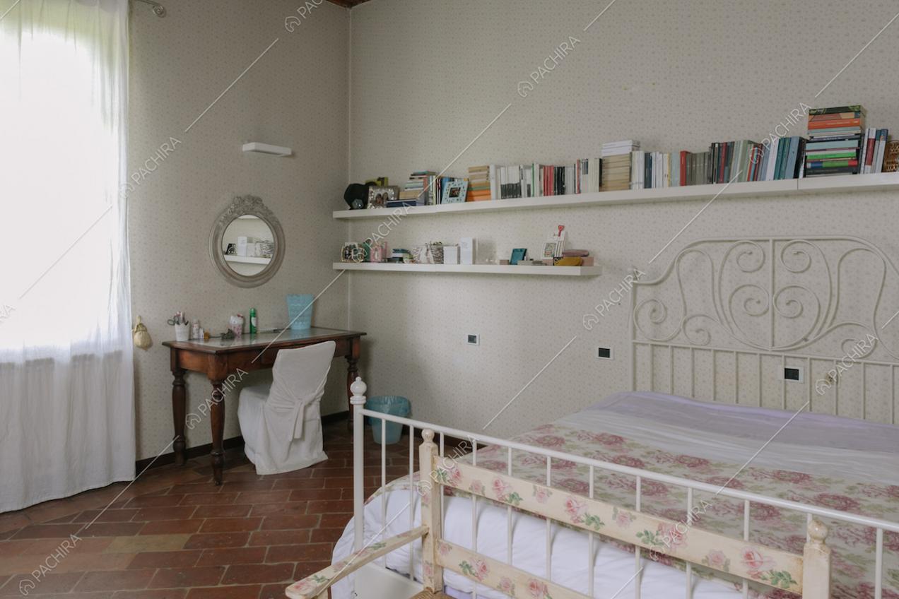 Camera da letto dai colori chiari e pavimento in pietra